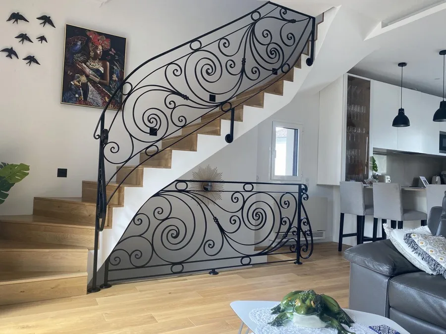 Rampe d'escalier courbée en fer forgé noir à volutes et arabesques, escalier en chêne, séjour contemporain, L'Art de Faire